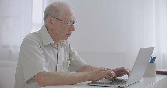 老年人在远程工作中打字通过在笔记本电脑上发送信息视频的预览图