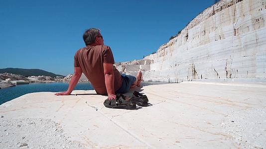 男人坐在阳光明媚的太阳台上在马赛多尼亚大理石湖帕穆穆视频的预览图