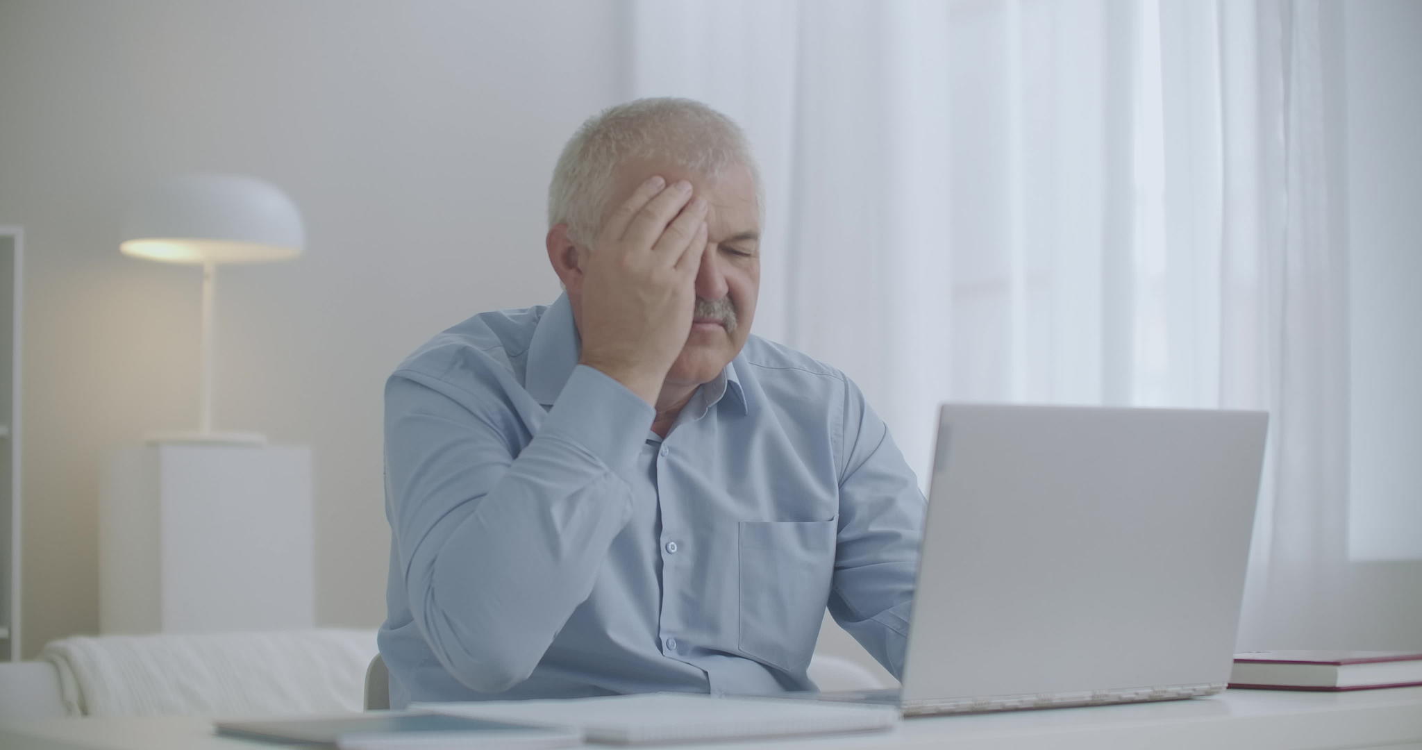 用笔记本电脑工作的男人会感到头痛、过度工作和疲劳视频的预览图
