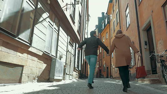 幸福的夫妇在狭窄的街道上奔跑视频的预览图