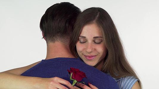 美丽的女人微笑着拥抱她的男朋友抱着红玫瑰视频的预览图