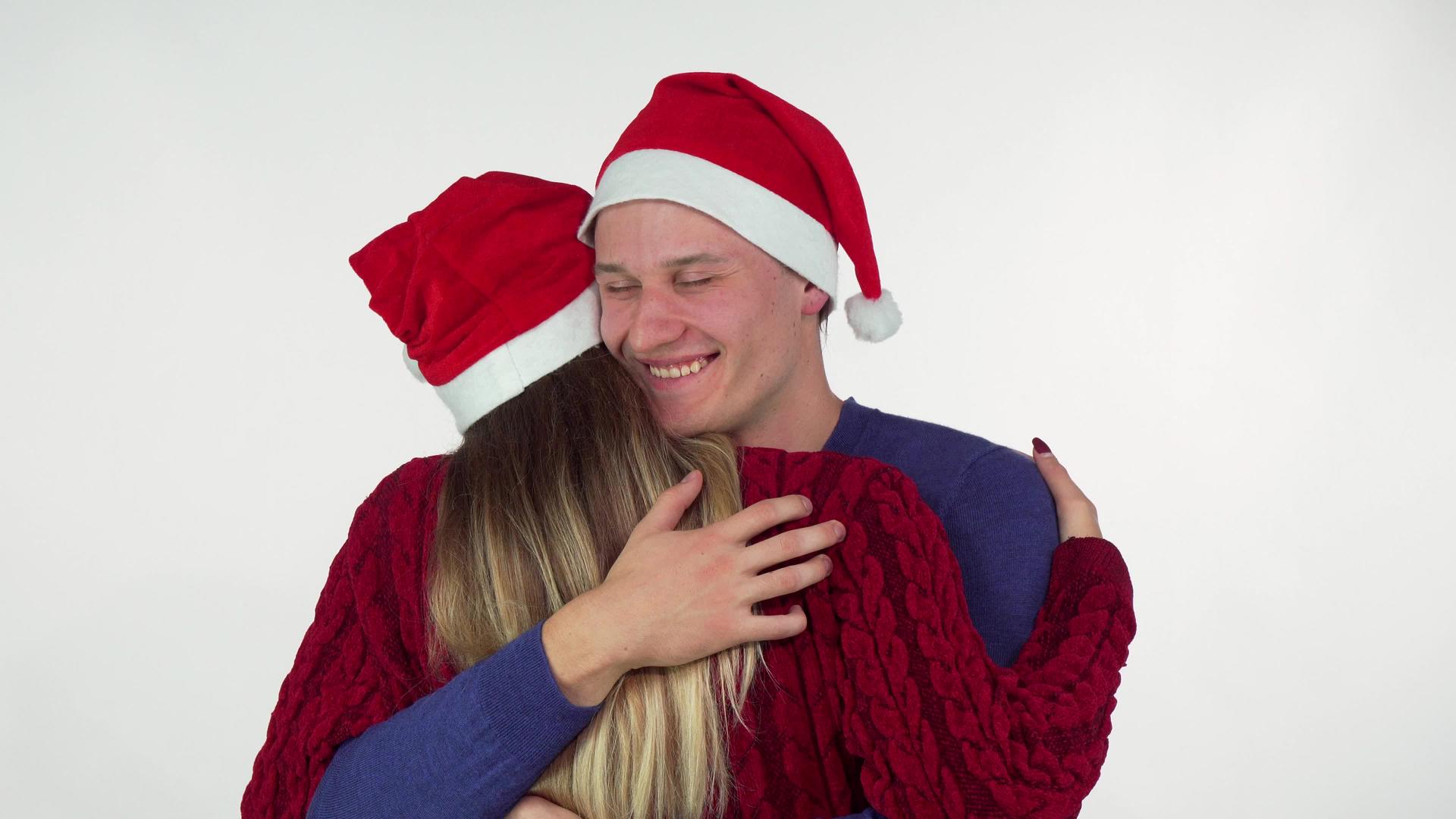 英俊的年轻人戴着圣诞帽拥抱他的女朋友视频的预览图