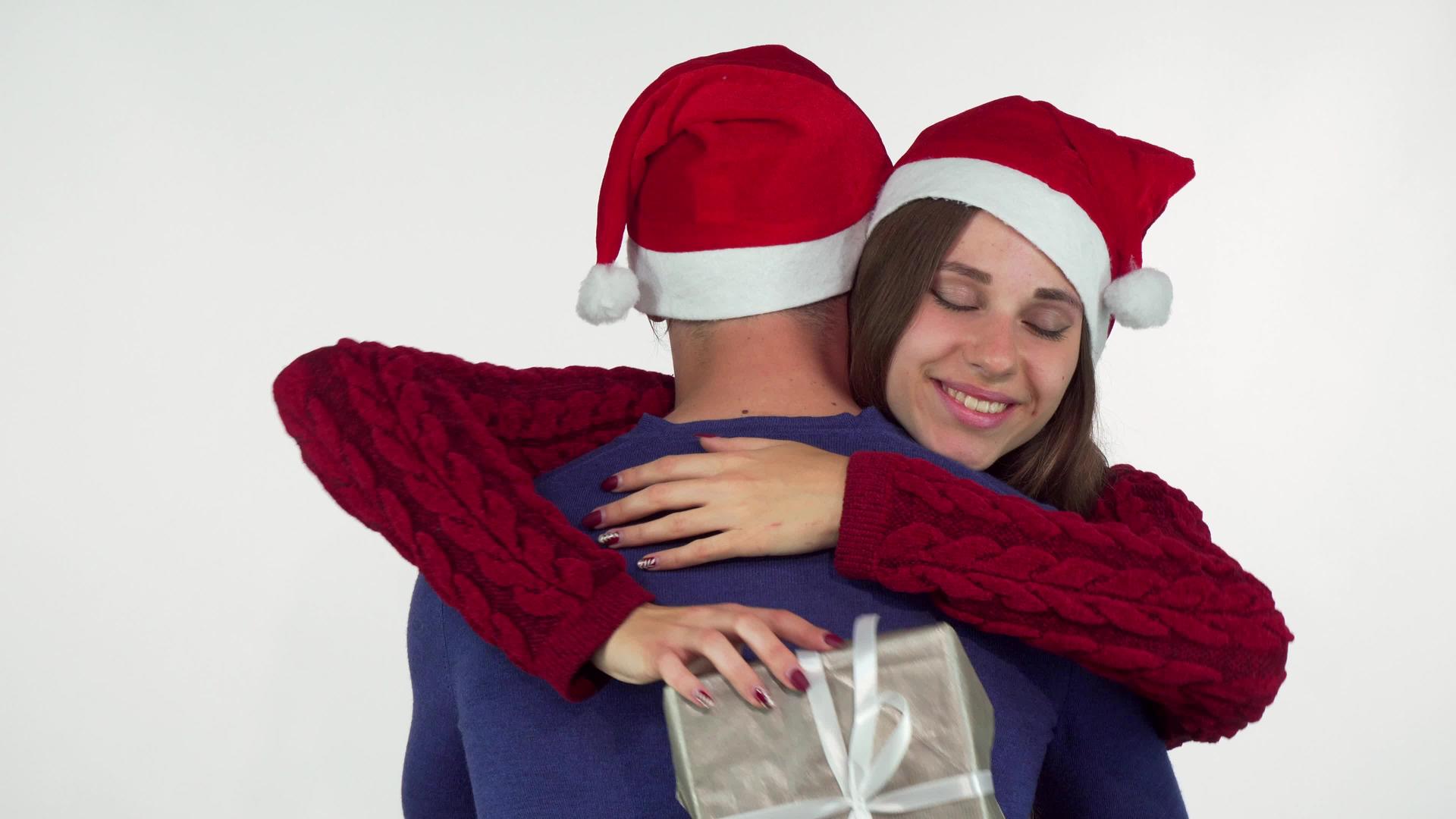 一个戴着圣诞帽的迷人年轻女子用礼物拥抱了她的男朋友视频的预览图