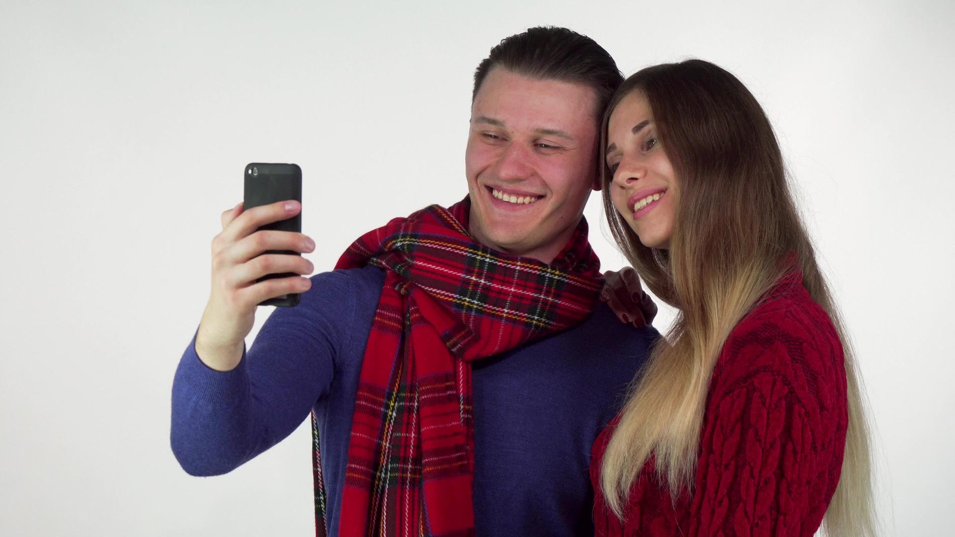 情侣们穿着温暖舒适的衣服用智能手机自拍视频的预览图