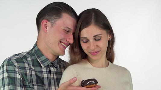 年轻男子微笑为漂亮的女朋友提供巧克力甜甜甜甜甜甜甜的圈视频的预览图