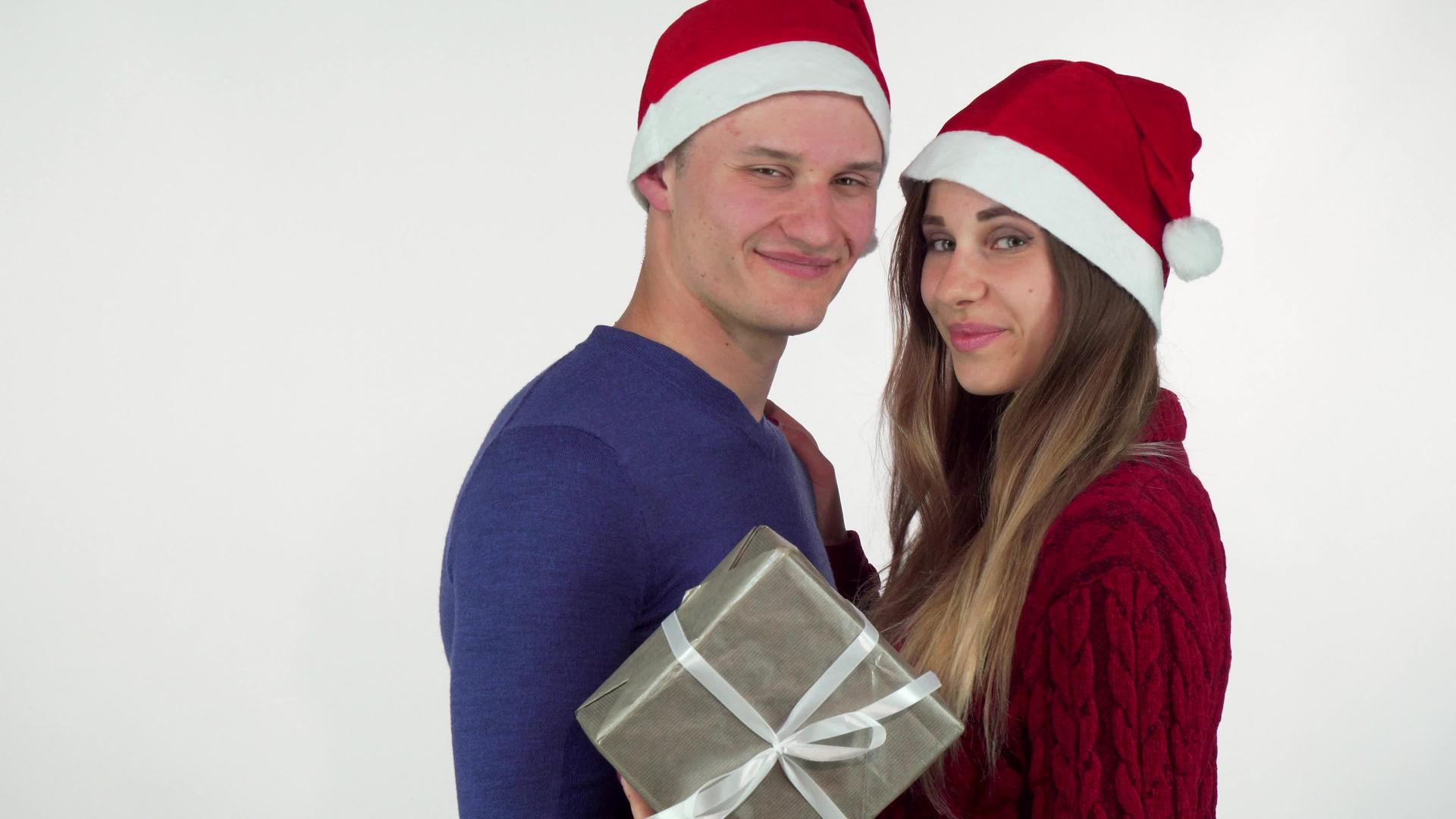 戴着圣诞帽的年轻情侣对着镜头微笑拿着礼物视频的预览图