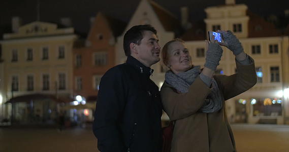 快乐的情侣晚上在街上打电话自拍视频的预览图