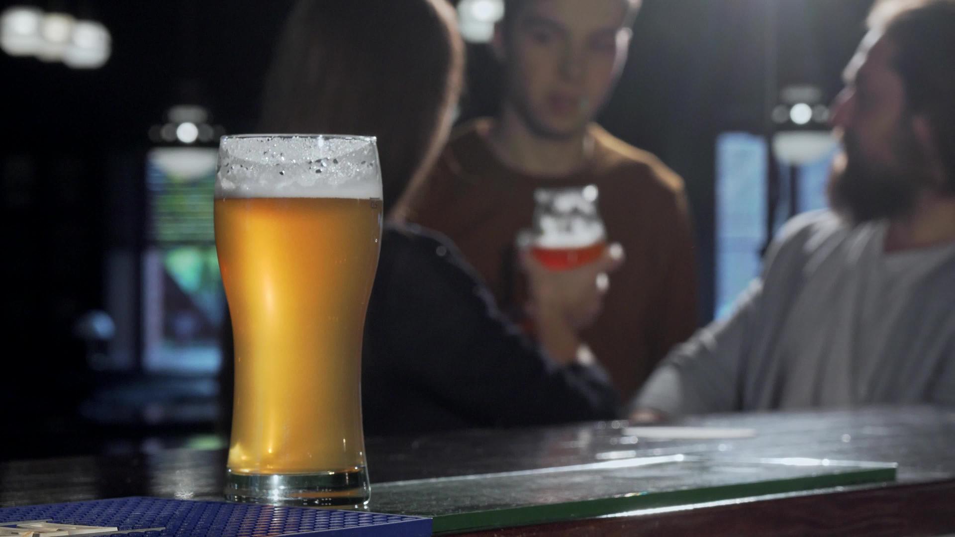 选择性的焦点放在啤酒杯上人们在酒吧里喝酒视频的预览图