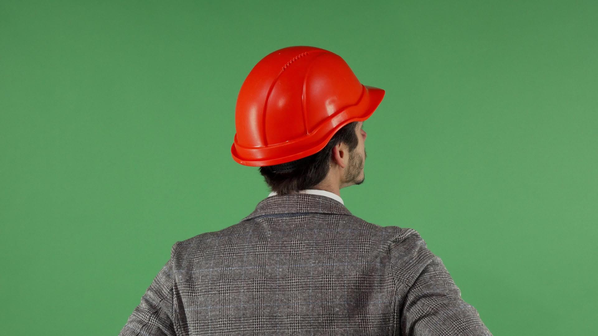 一位戴着硬帽的承包商抬头看着绿屏背面的肖像视频的预览图