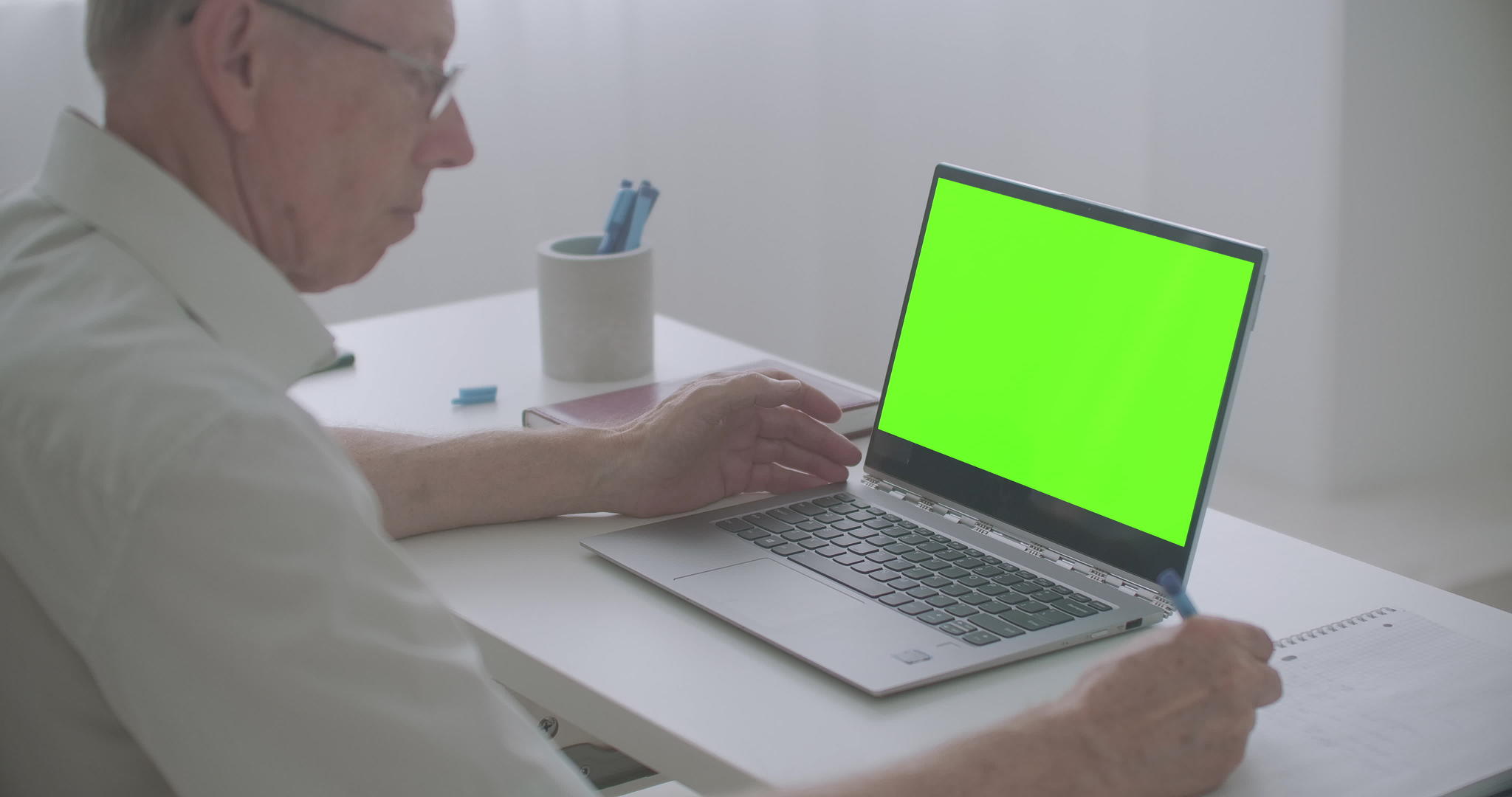 老人正在看笔记本电脑屏幕和笔记生产后使用笔记视频的预览图