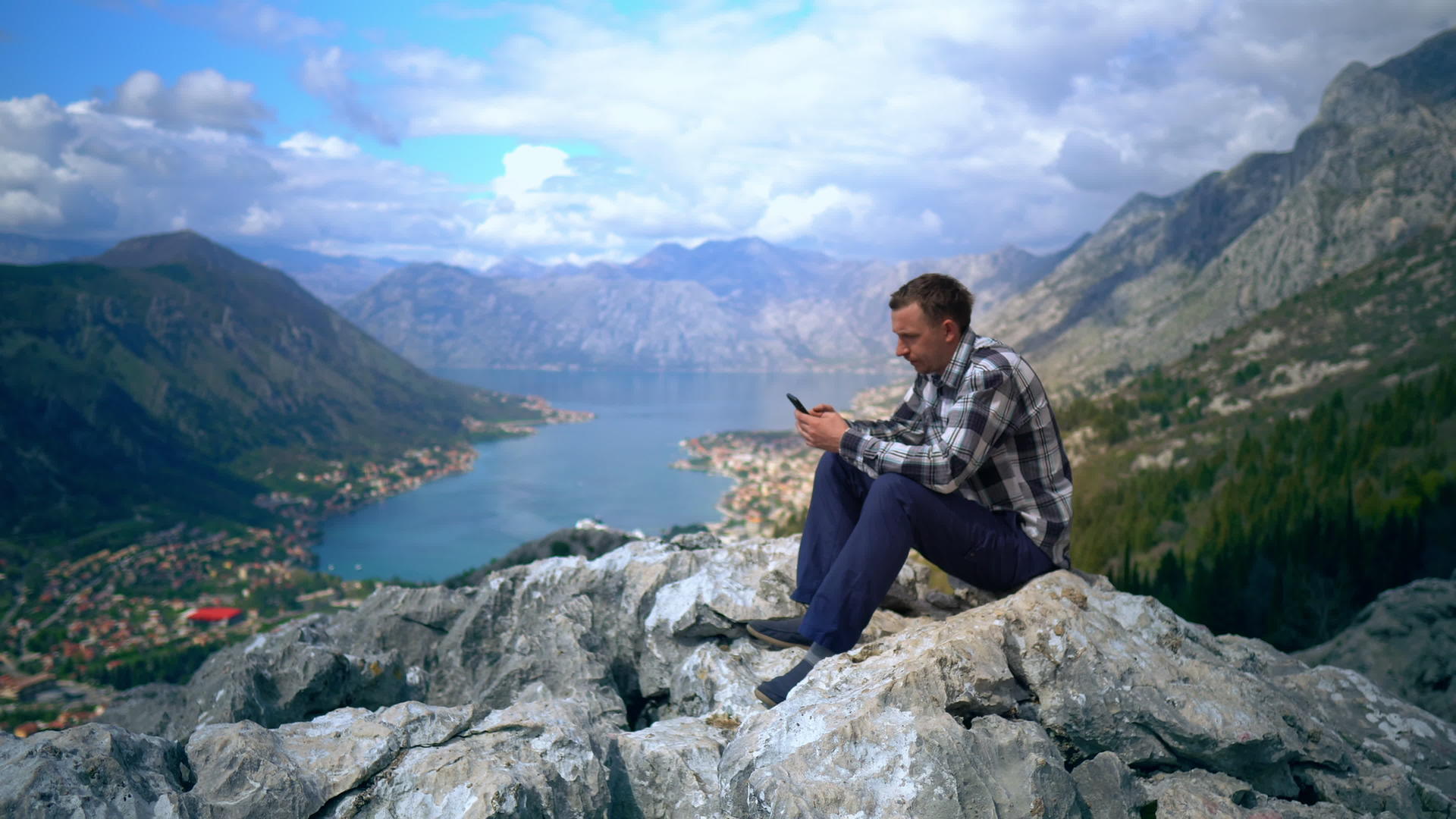 年轻的男性青年坐在山顶上视频的预览图