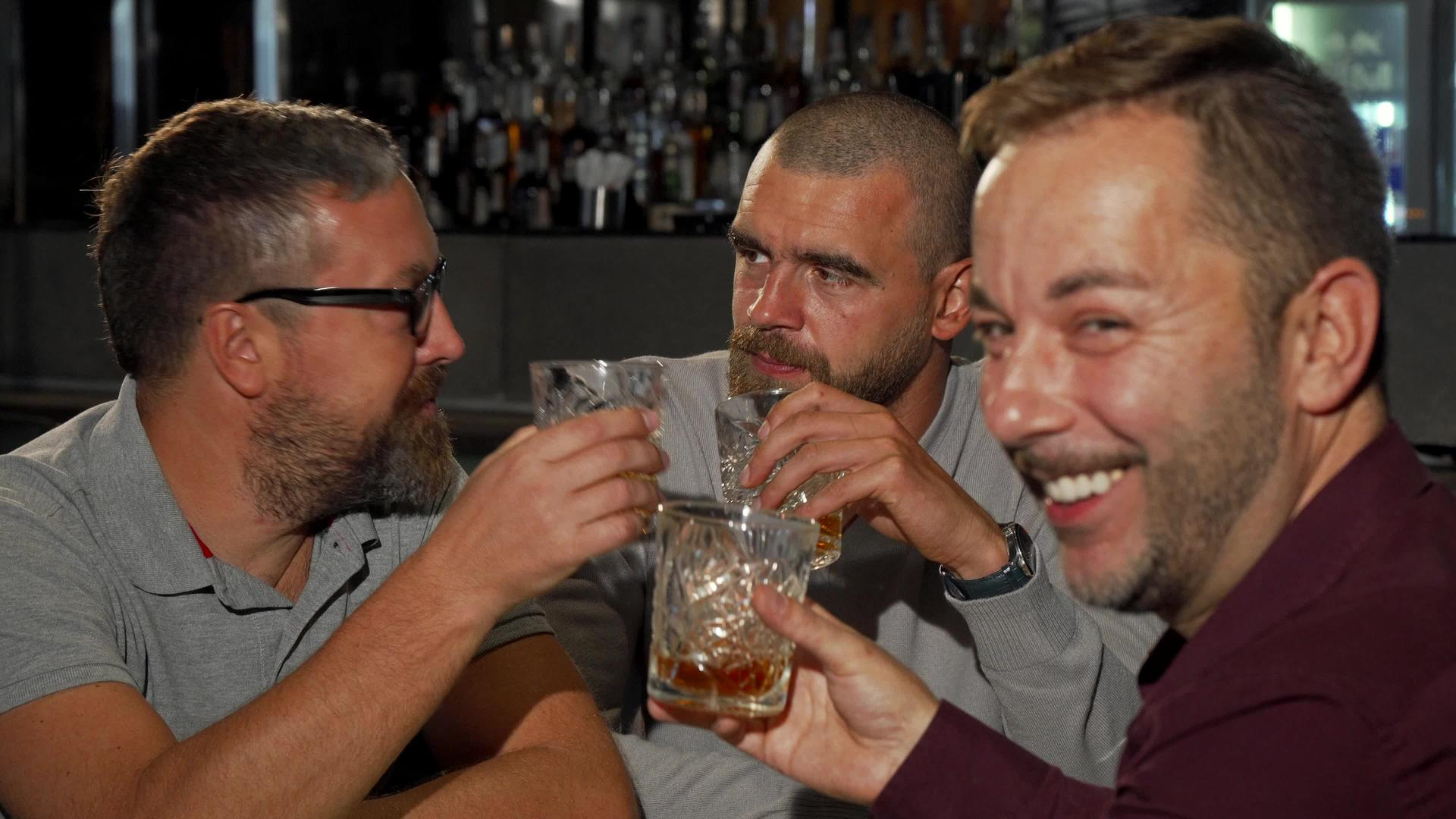 快乐的成熟男人对着镜头微笑和朋友一起喝威士忌视频的预览图
