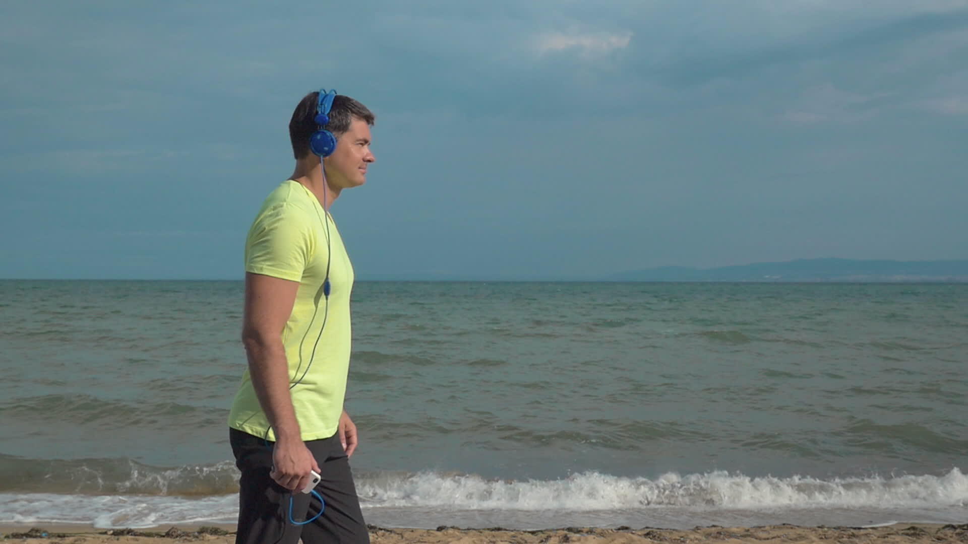 男人用智能手机在海滩上慢跑视频的预览图