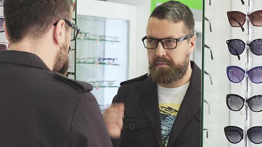 成熟的男人在面试前戴新眼镜如果商店的镜子视频的预览图