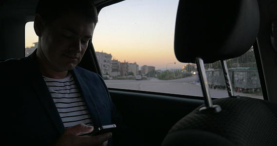 男人在汽车上浏览互联网在智能手机上视频的预览图