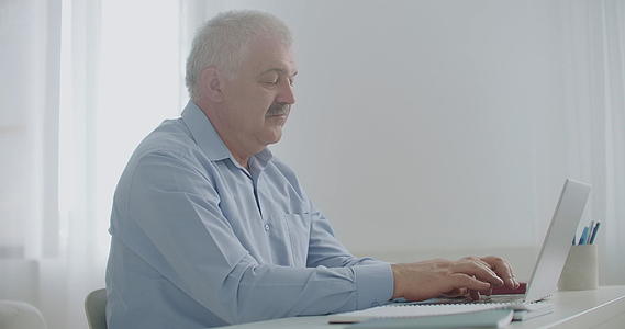 工作日成年男子在办公室的笔记本电脑键盘上打字视频的预览图