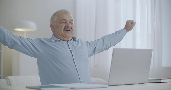 在用笔记本电脑工作期间老人伸出手肩膀坐在桌子上打字视频的预览图