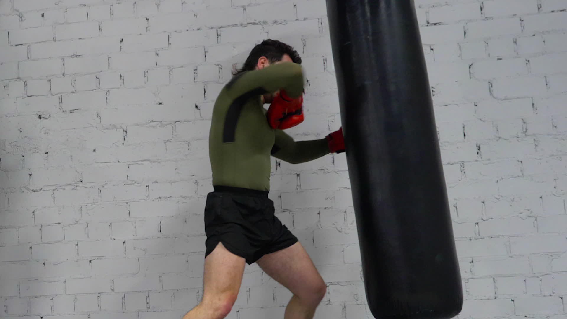 在拳击俱乐部男拳击手戴着膝盖和肘部拳击袋的手套视频的预览图