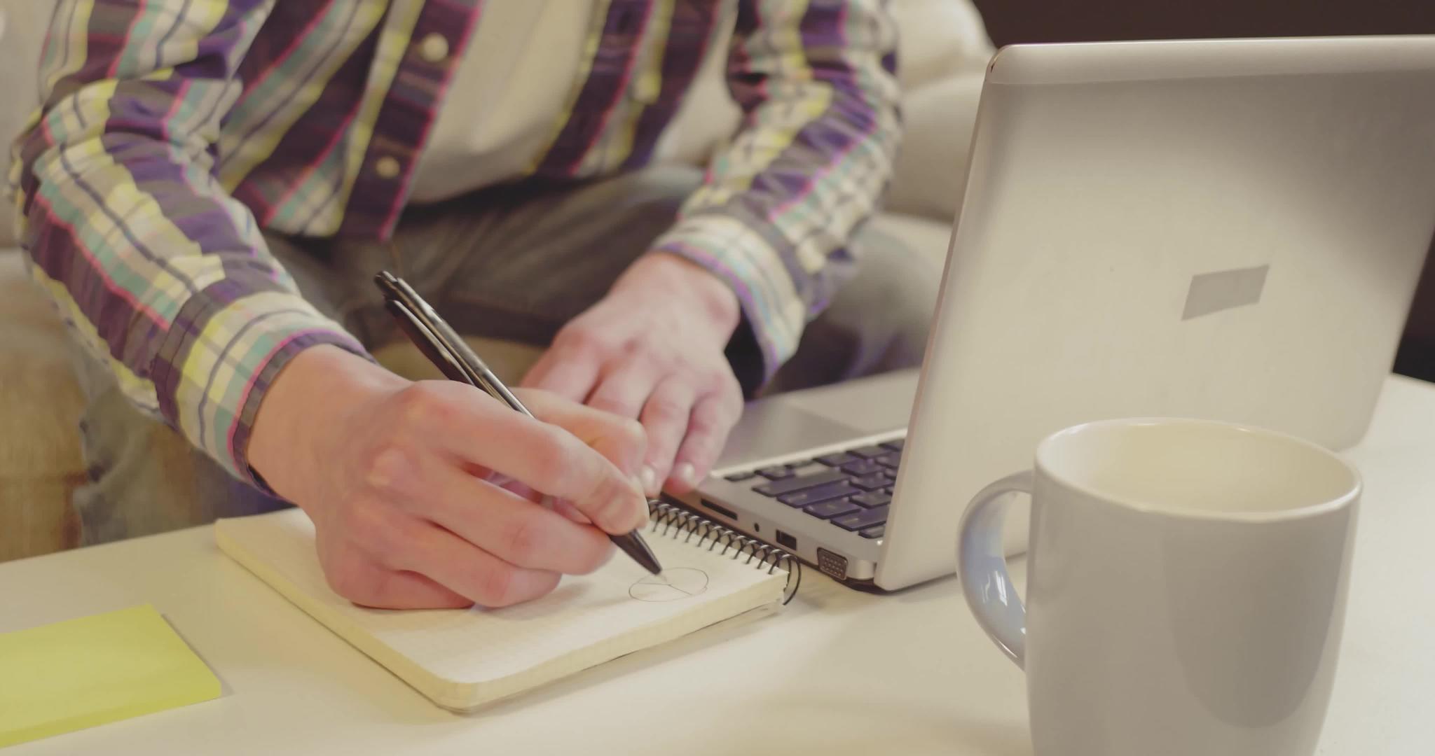 在家工作的学生或在笔记本上做笔记的自由职业者视频的预览图