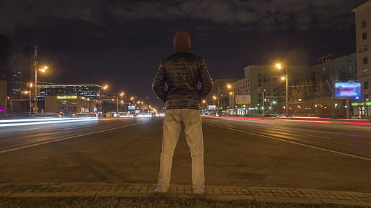 这名男子在夜间站立车辆在高速公路上行驶时间已经过去了城市已经过去了视频的预览图