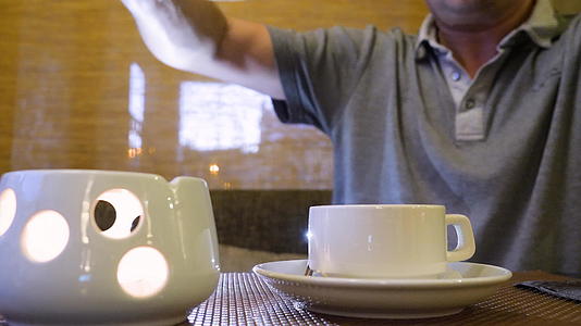 男人拿着茶壶喝茶然后把热茶倒进桌子上的杯子里视频的预览图