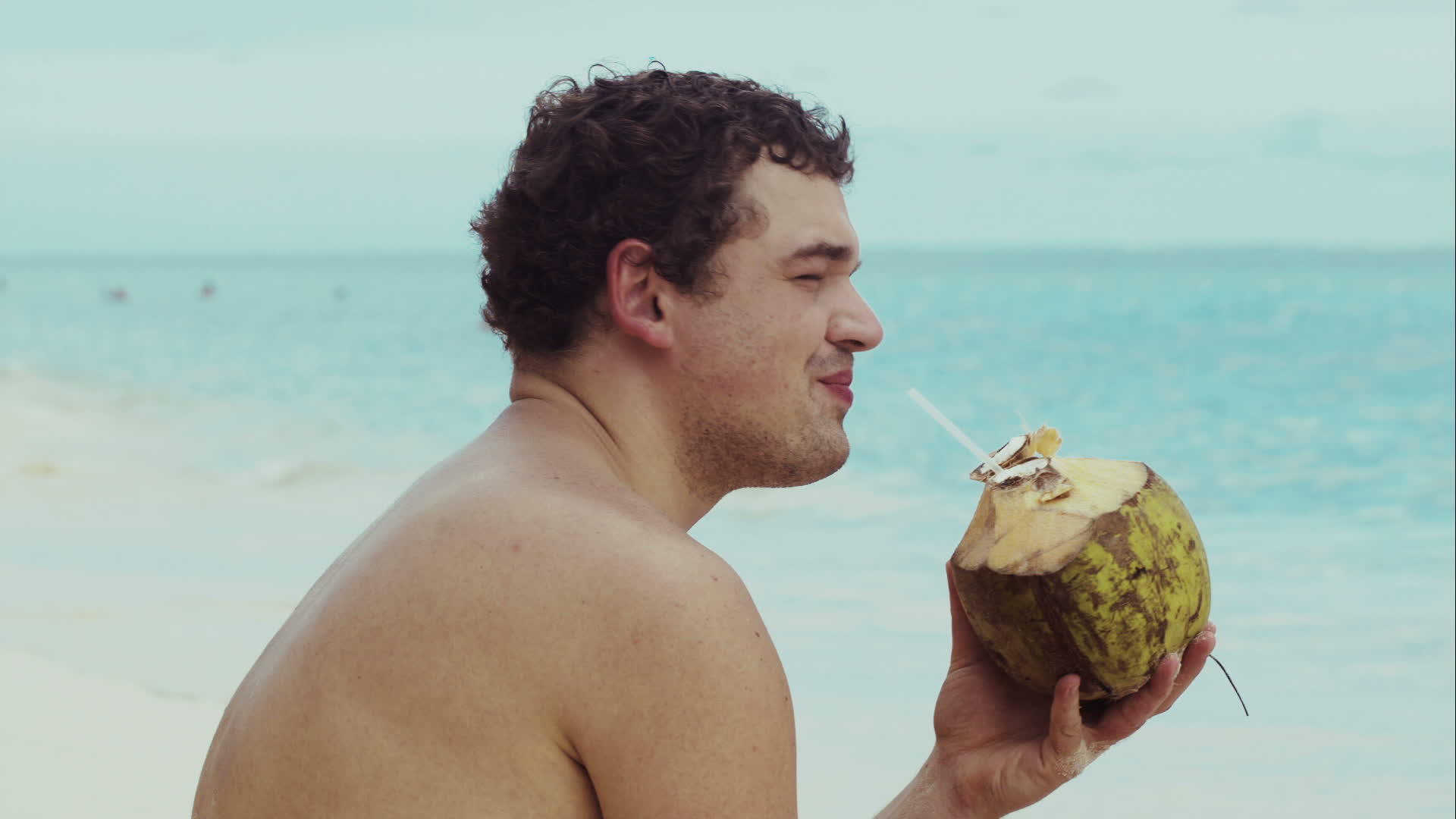 男人在海滩上喝椰子酒视频的预览图