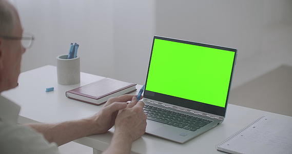 退休男子使用笔记本电脑和视频聊天Pc在绿色屏幕上进行视频的预览图