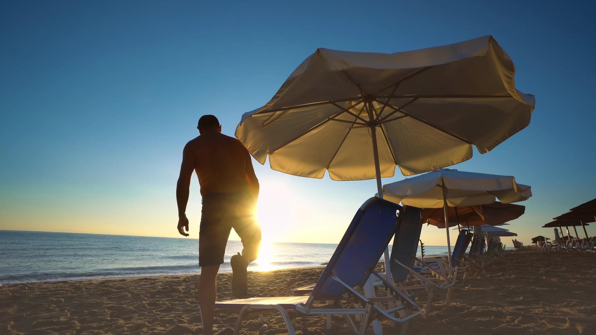 男人躺下享受美丽宁静的日出在开阔的海滩上享受美丽宁静的日出视频的预览图