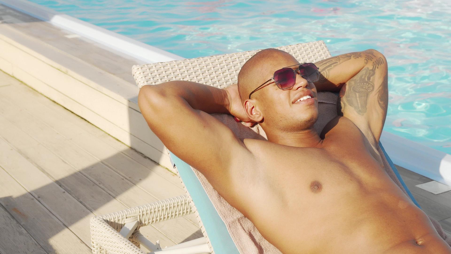 一个英俊的非洲男子在游泳池旁边日光浴视频的预览图