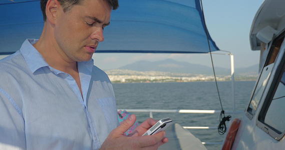 男人在游艇上使用智能手机视频的预览图