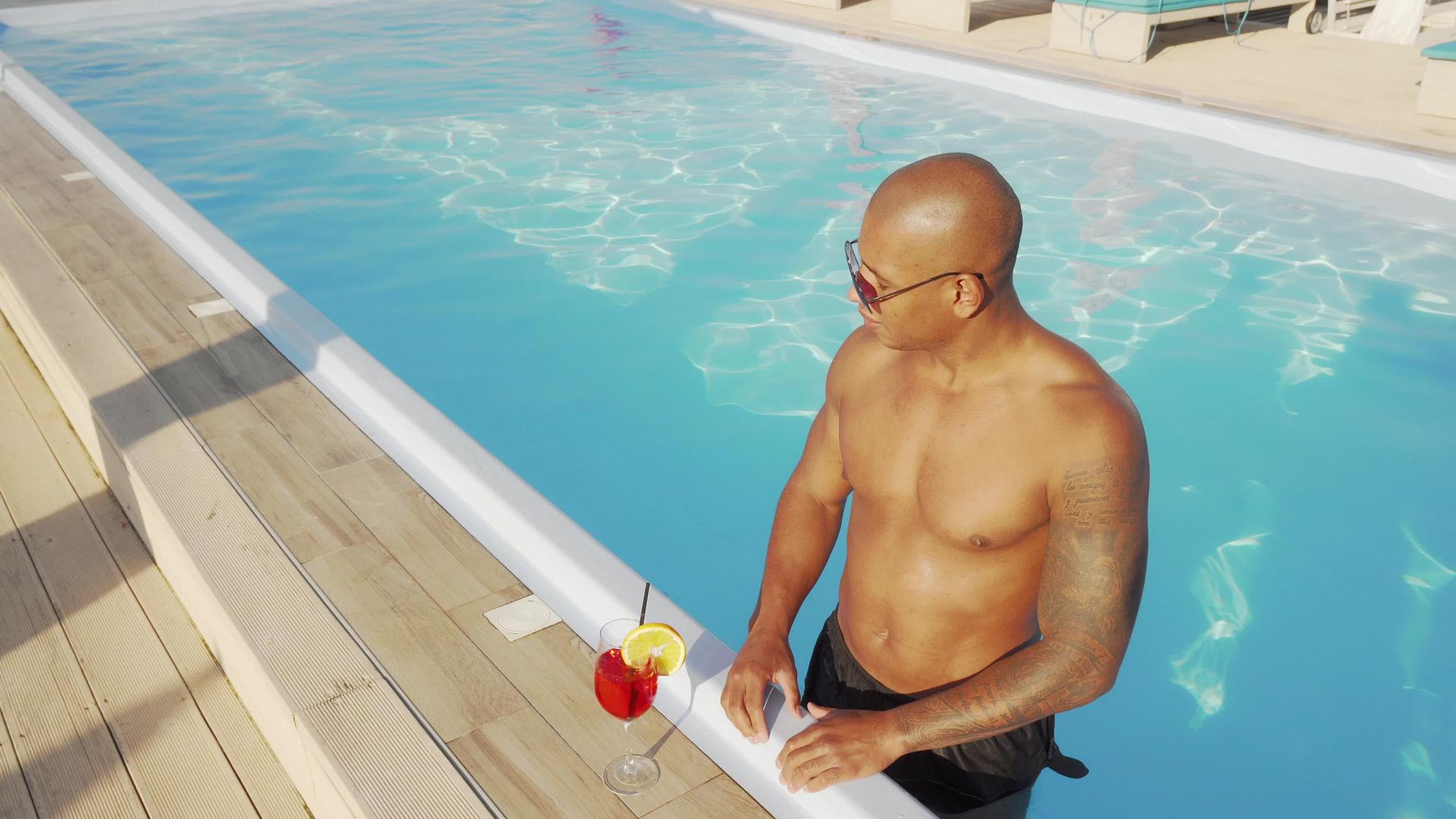 英俊的非洲男人喜欢在游泳池里喝鸡尾酒视频的预览图