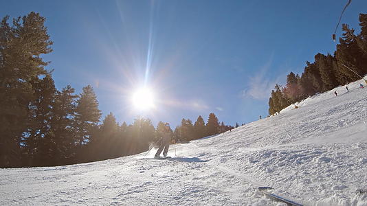 男子在雪坡上滑雪在山上滑雪度假胜地从太阳背慢慢下来视频的预览图
