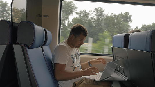 男子在乘坐通勤列车时使用膝盖电脑视频的预览图