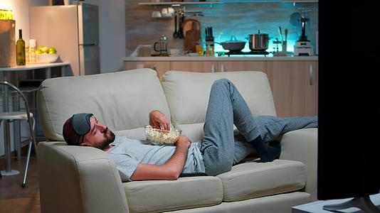 男人躺在沙发上睡在电视的角落里视频的预览图