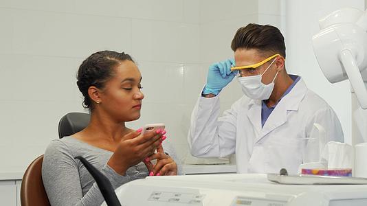 年轻快乐的女士和她的牙医对着镜头微笑视频的预览图