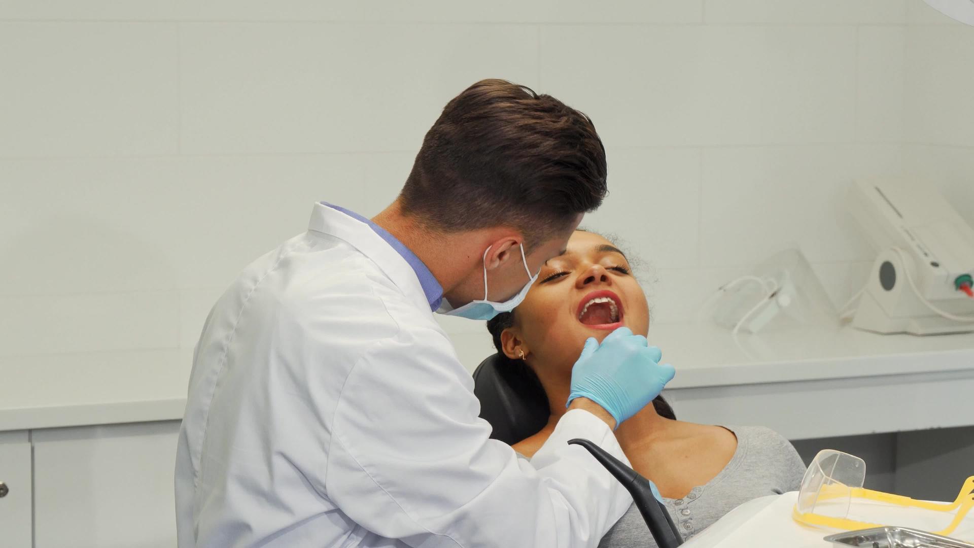 男性牙医在检查女性患者的牙齿时微笑视频的预览图