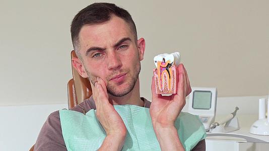 年轻人牙痛地坐在诊所的牙椅上；男人；视频的预览图
