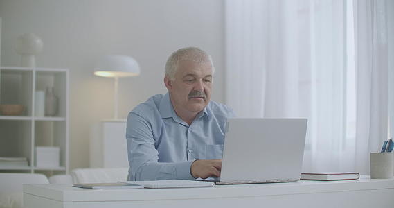 牙痛男子在家庭办公室用笔记本电脑擦脸颊、牙齿和牙齿视频的预览图