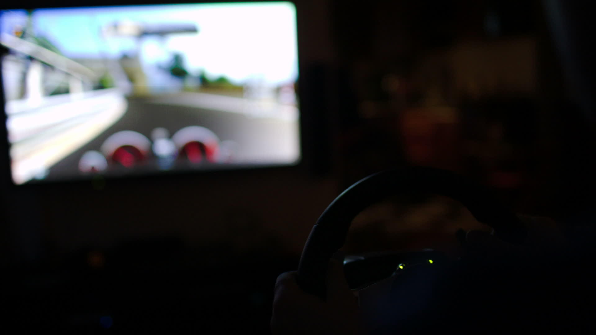 男人在黑暗中用方向盘玩赛车游戏视频的预览图