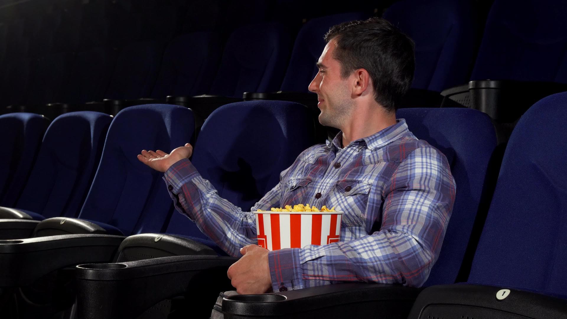 快乐的帅哥笑着坐在电影院里视频的预览图