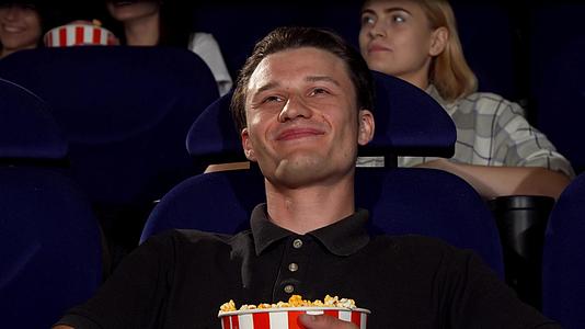 快乐迷人的男人在电影院的相机里微笑视频的预览图