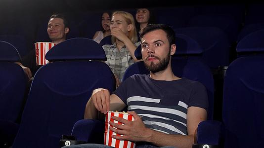 在电影院看电影时快乐的年轻人举起拇指视频的预览图
