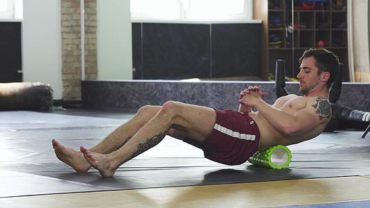 运动肌肉男在训练后休息使用泡沫滚动视频的预览图