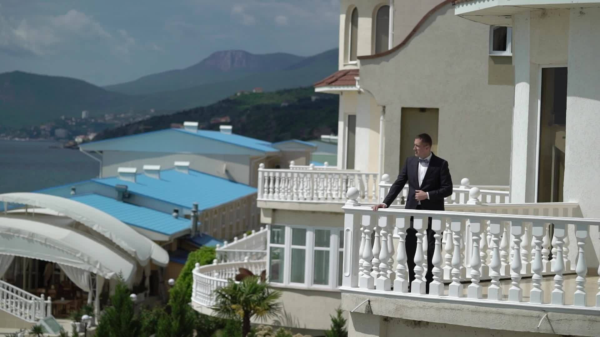一个穿着经典黑色西装的男人住在阳台商人或新郎附近视频的预览图