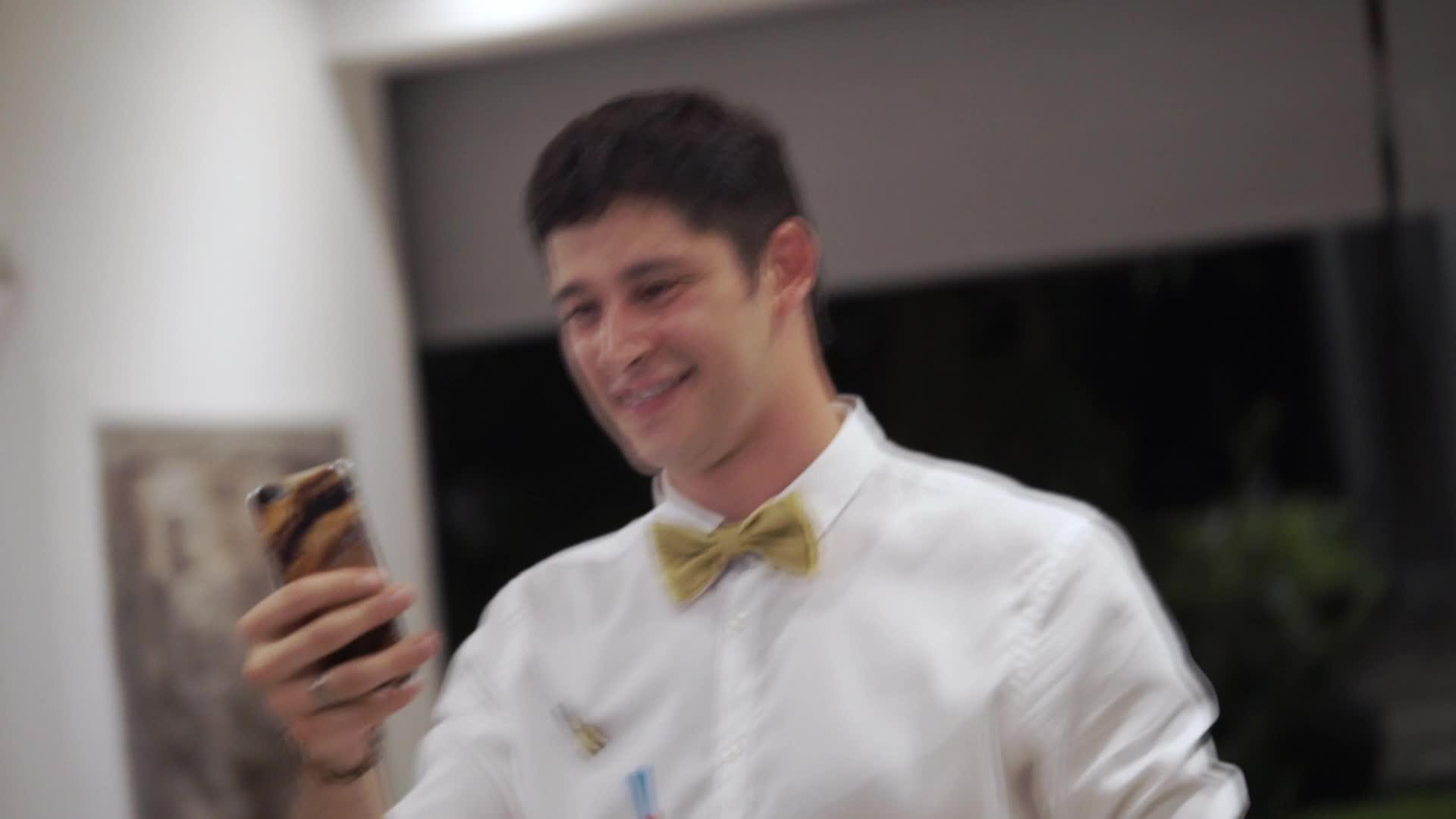 晚上一名年轻男子在热带别墅的一个聚会上用手机拍照视频的预览图
