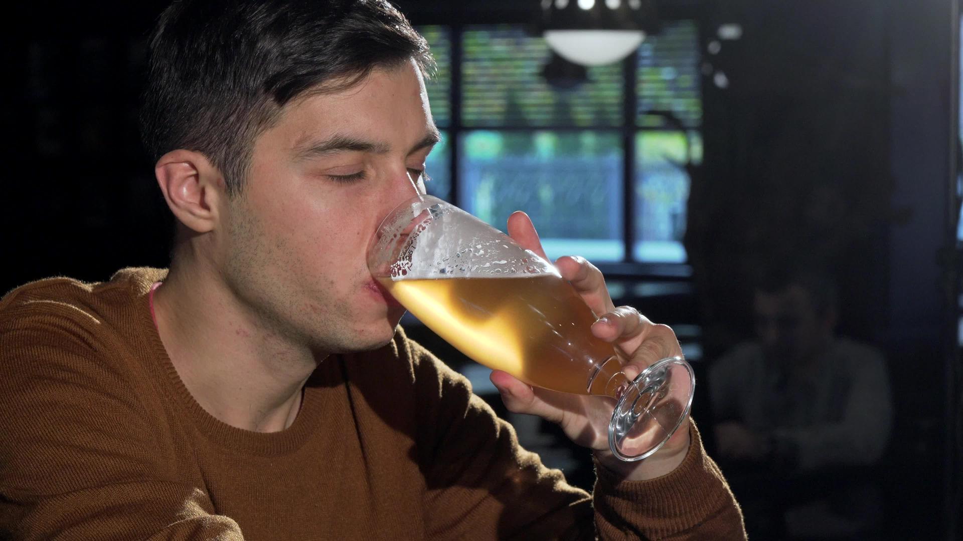 吸引人的男人从酒杯里喝美味的啤酒在酒吧里放松视频的预览图