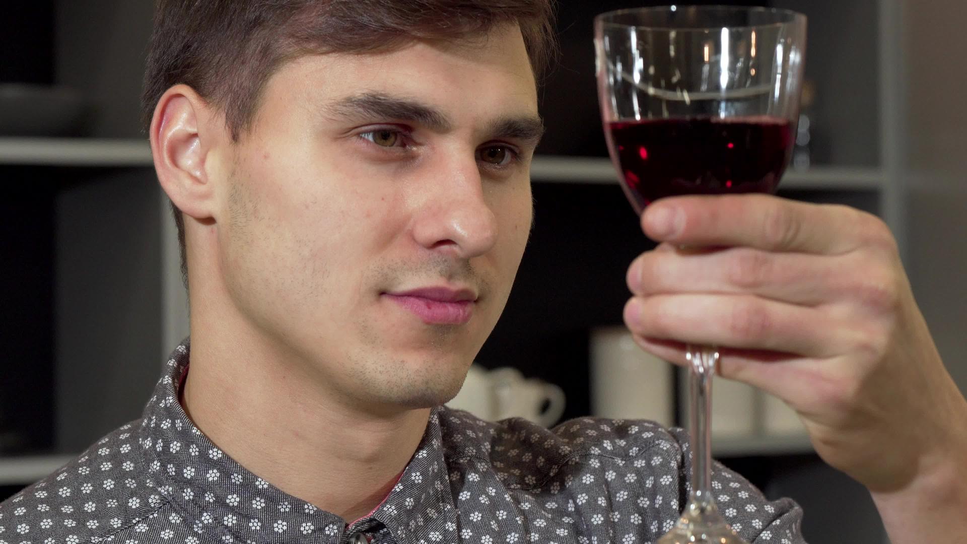 英俊的男人闻到美味的红酒在家里放松视频的预览图