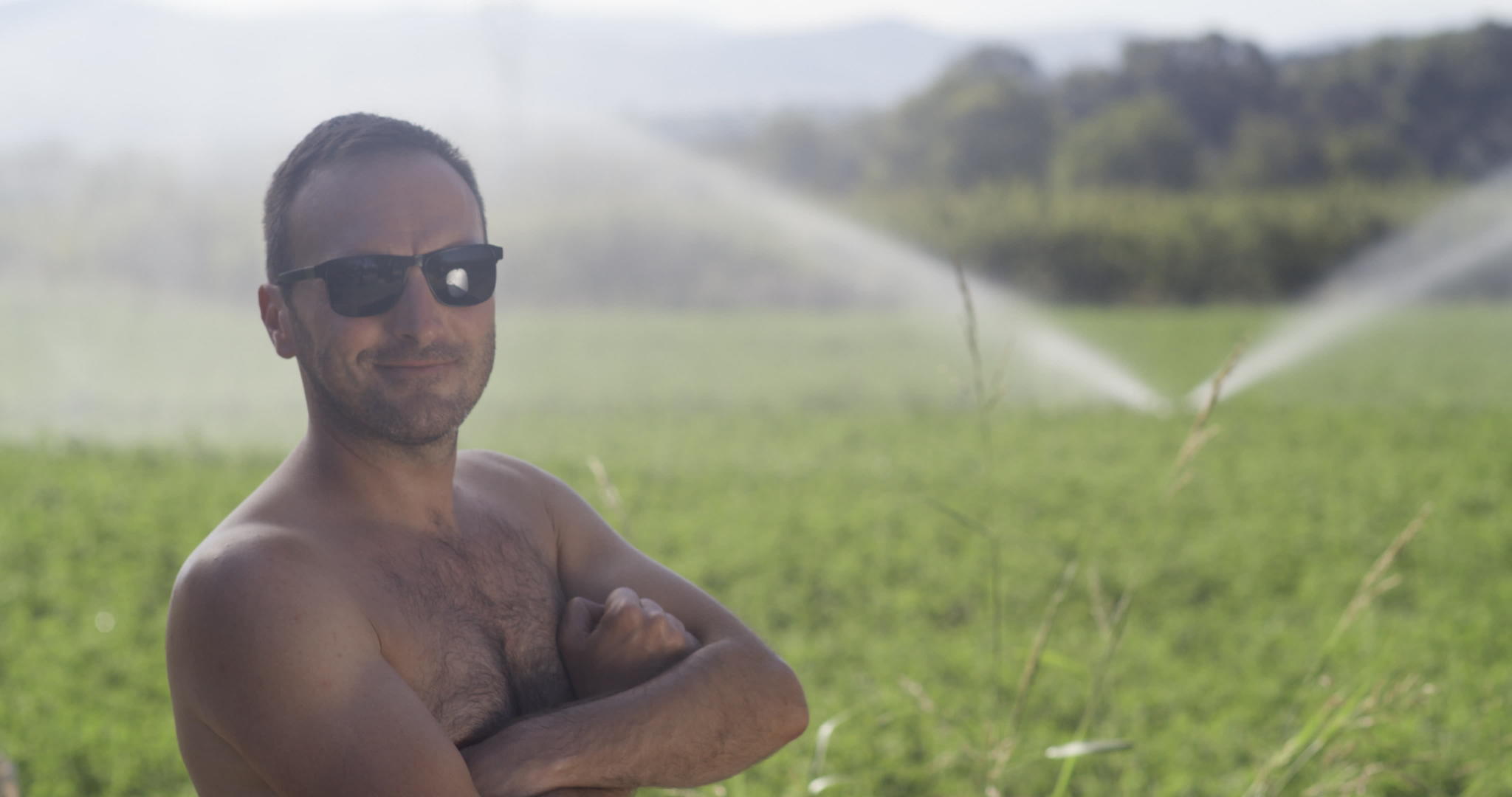 没有衬衫的农业工人在有灌溉系统的绿地上竖起大拇指视频的预览图