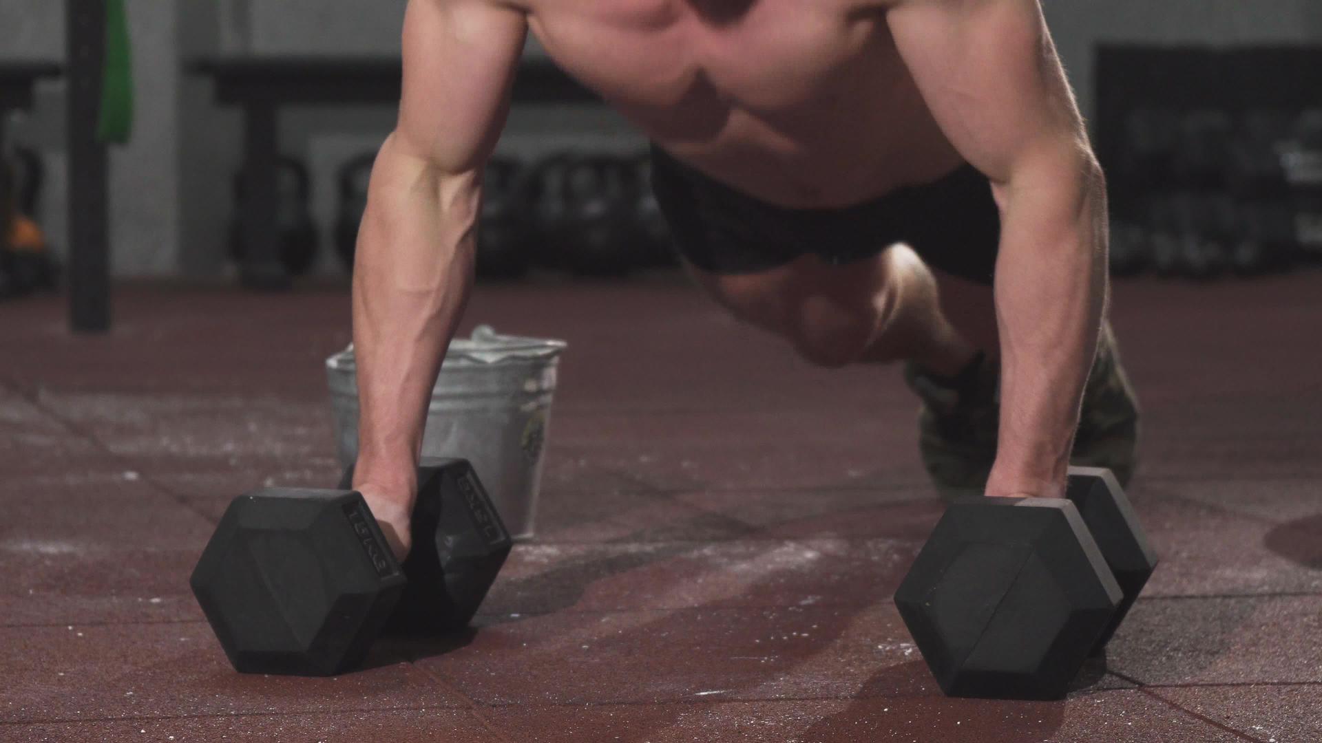 一个强壮的肌肉男在健身房用哑铃做俯卧撑视频的预览图