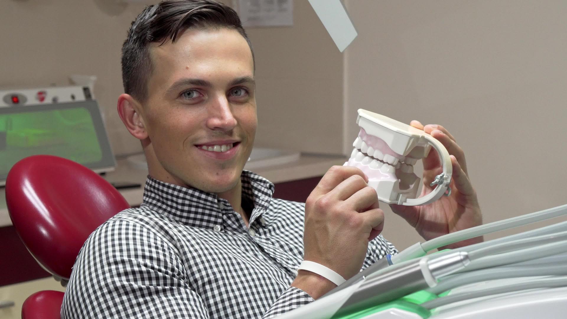英俊的年轻人检查牙科模具对着镜头微笑视频的预览图